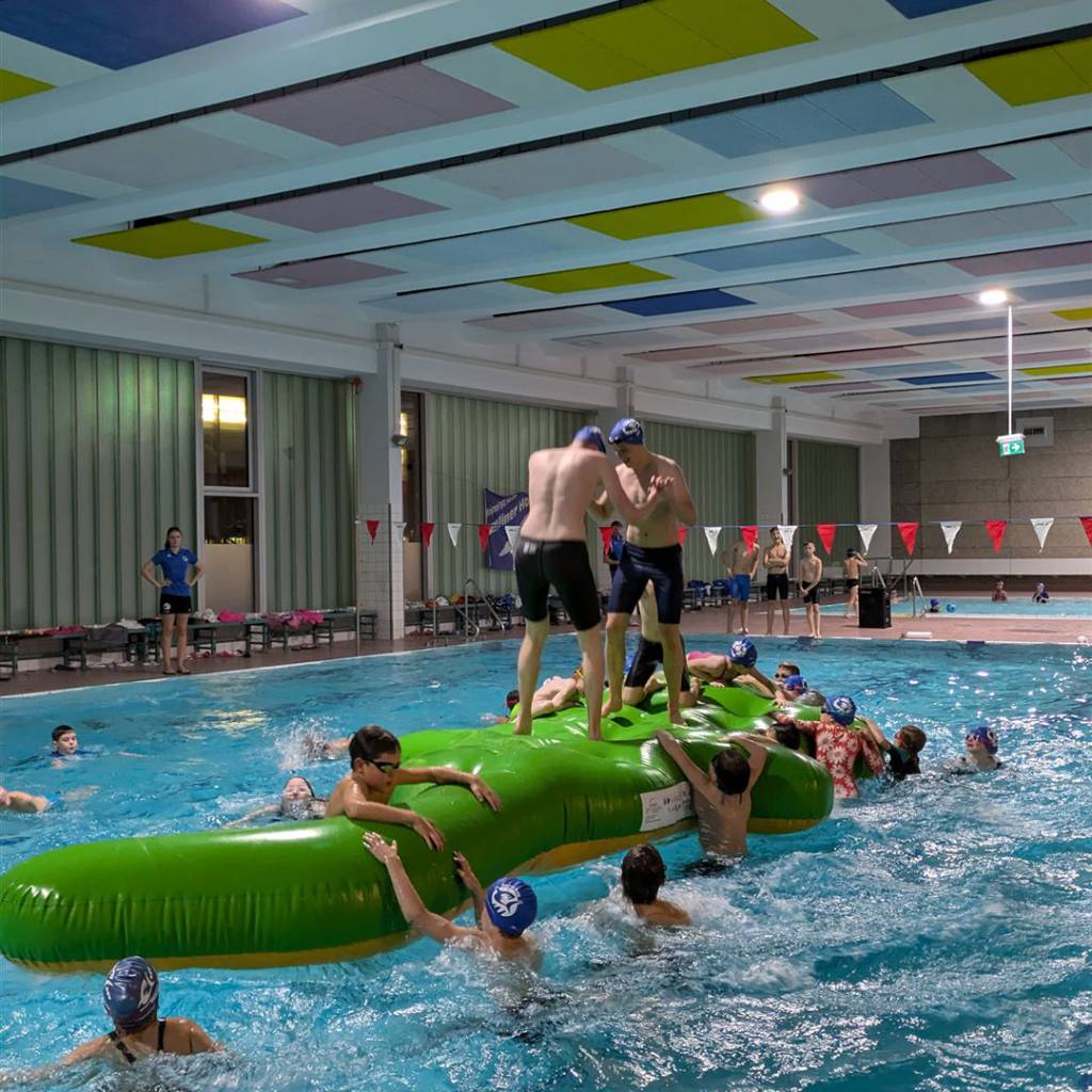Kinder spielen auf einem aufblasbaren Krokodil im Schwimmbecken