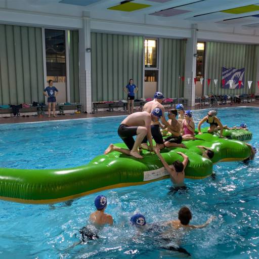 Kinder spielen auf einem aufblasbaren Krokodil im Schwimmbecken