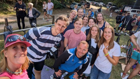 Eine große Gruppe von Menschen posiert lächelnd zusammen nach einer gemeinsamen Outdoor-Aktivität.