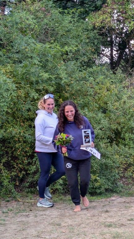 Zwei lächelnde Frauen stehen inmitten dichter Vegetation und feiern einen gemeinsamen Erfolg.