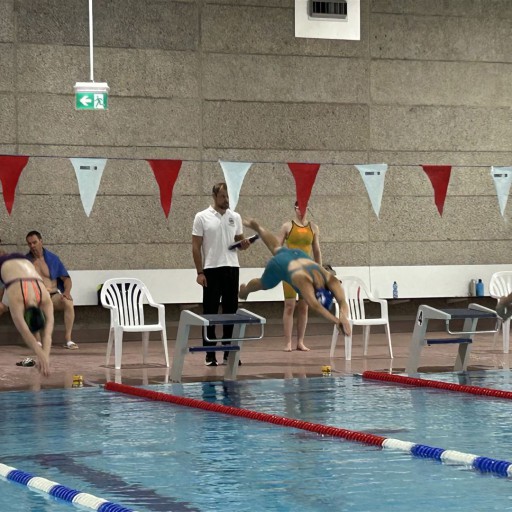 Großes Hallenbad mit Badegästen und Schwimmbahnen.